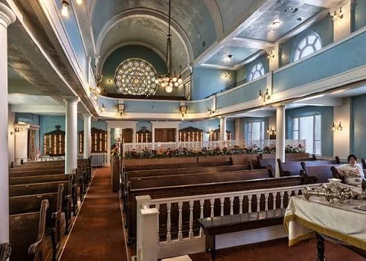 Interior of Beth Tephilah Synagogue in Troy, with wooden pews, balconies and a stained-glass window